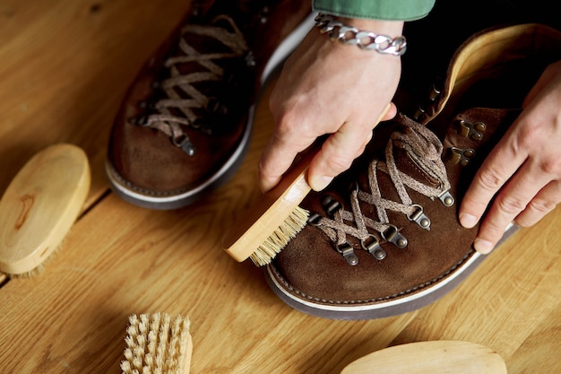 La mano dell'uomo pulisce le scarpe scamosciate con la spazzola