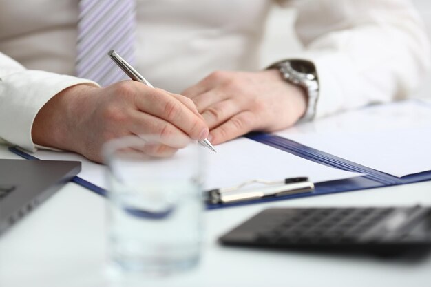 La mano dell'uomo tiene la penna e compila il programma della giornata lavorativa