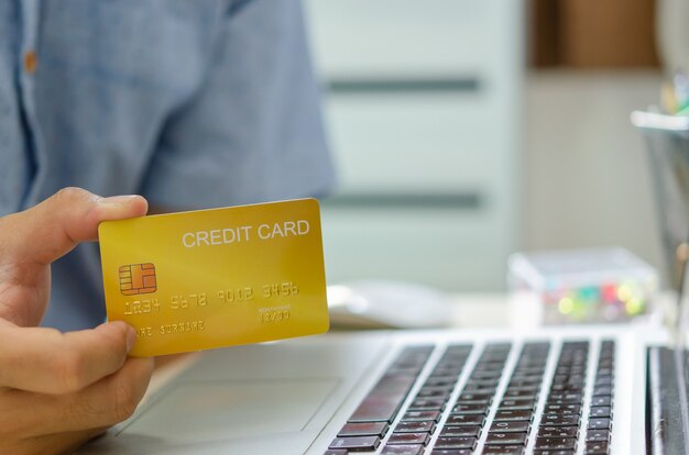 La mano dell'uomo tiene una carta di credito per le transazioni in linea o lo shopping in linea. Richiedere una carta di credito, fare un prestito finanziario