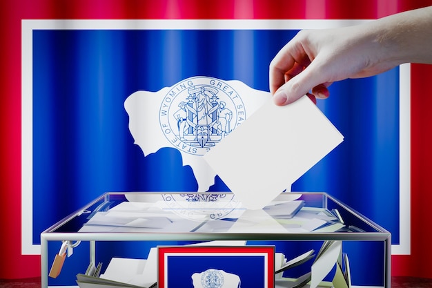 La mano della bandiera del Wyoming che fa cadere la scheda elettorale in un'illustrazione 3D del concetto elettorale di voto della scatola