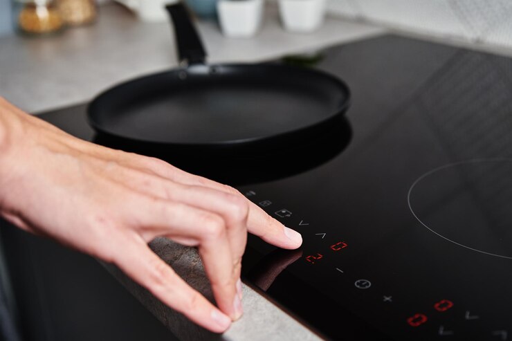 La mano della donna accende la moderna stufa a induzione in cucina