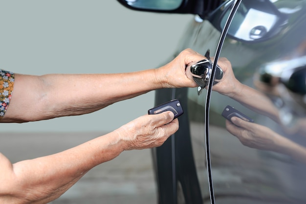 La mano della donna anziana apre l'auto sui sistemi di allarme chiave dell'auto