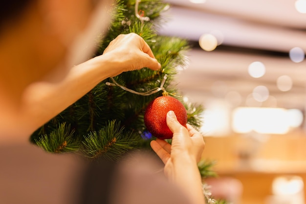 La mano della donna appendere una palla di Natale sulla festa dell'albero di Natale festivo