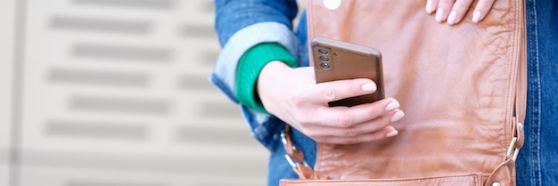 La mano della donna apre una borsa e tiene lo smartphone che riceve un messaggio o un concetto di notifica