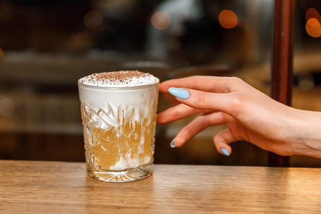 La mano della donna che cerca un cocktail al bar