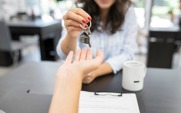 La mano della donna che consegna la chiave di casa, concetto di acquisto della casa