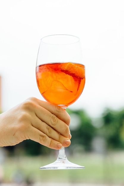 La mano della donna che tiene un bicchiere di bevanda alcolica in estate per strada. concept drink su una terrazza in strada