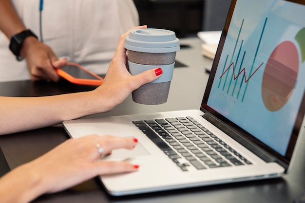 La mano della donna che tiene un caffè mentre usa il computer