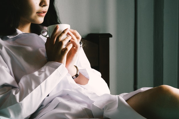 La mano della donna che tiene una tazza di caffè rossa. Con una bella manicure invernale. Tonalità di guadagno del film