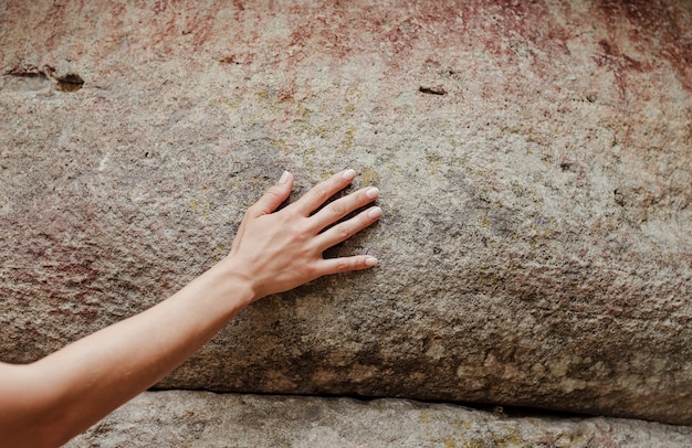 La mano della donna che tocca la superficie della roccia