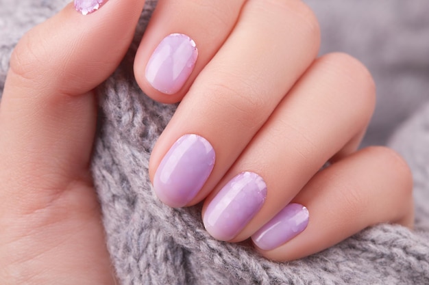 La mano della donna con il design delle unghie di Natale invernale con manicure alla lavanda alla moda