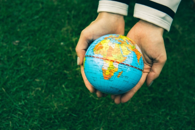 La mano della donna con il globo su fondo verde.