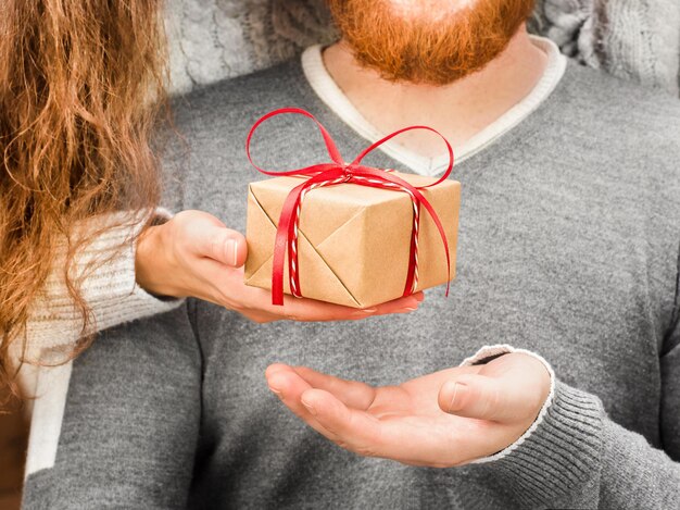 La mano della donna dà una confezione regalo a un uomo in primo piano