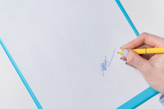 La mano della donna mette la sua firma su un foglio di carta. Accedi al documento. Primo piano, copia spazio, motivo sullo sfondo