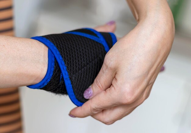 La mano della donna mette una benda di fissaggio sul polso Protezione dalle lesioni Fissaggio della mano ferita