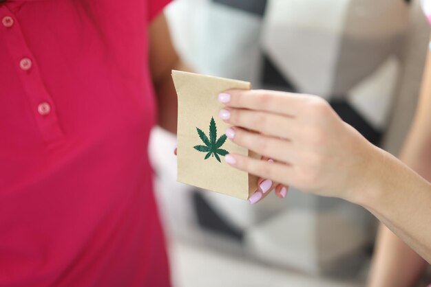 La mano della donna passa il sacchetto di carta con e il primo piano della marijuana