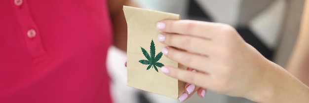 La mano della donna passa il sacchetto di carta con e il primo piano della marijuana