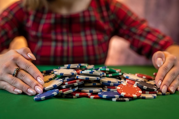 La mano della donna prende le fiches da poker da una pila a un tavolo da poker rotondo