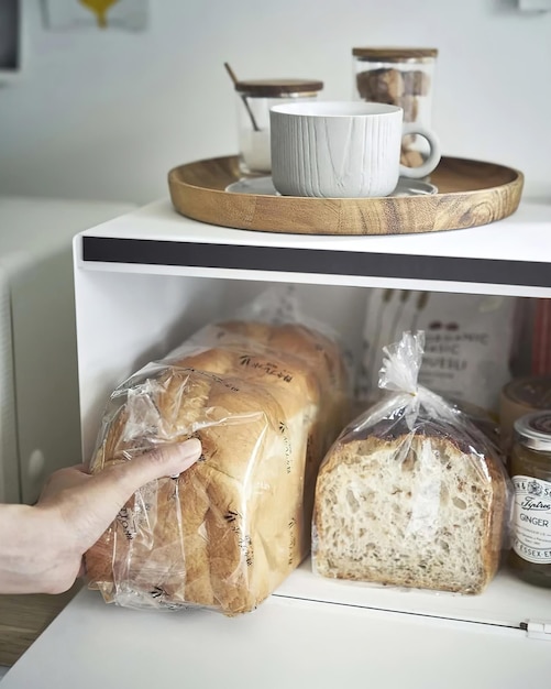 La mano della donna prende un pane da una scatola di pane