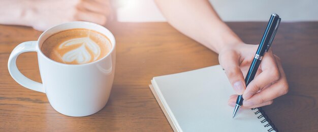 La mano della donna sta scrivendo sul blocco note con una penna in ufficio