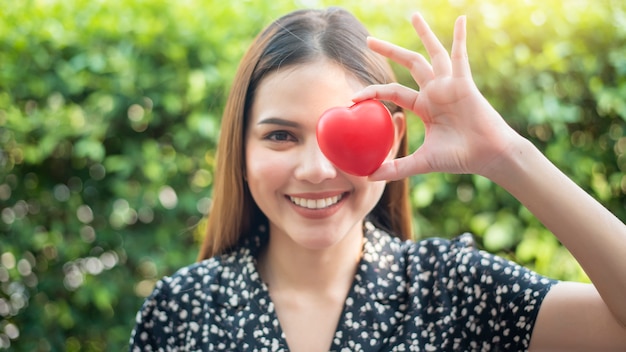 La mano della donna sta tenendo il cuore rosso