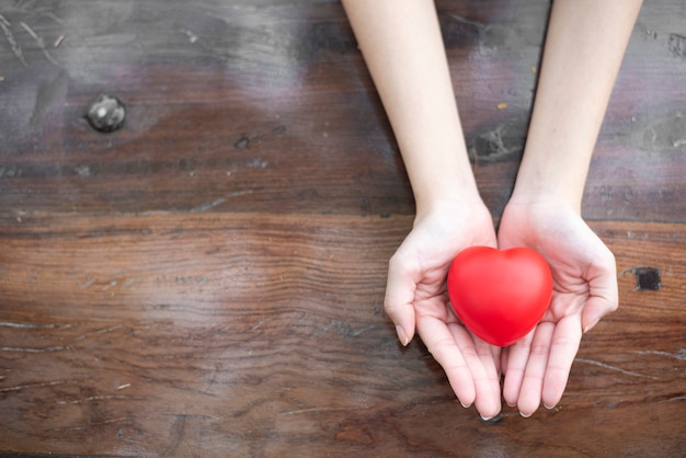 La mano della donna sta tenendo il cuore rosso