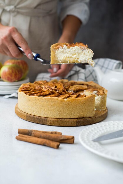 La mano della donna sta tenendo un pezzo di torta di mele con la cannella