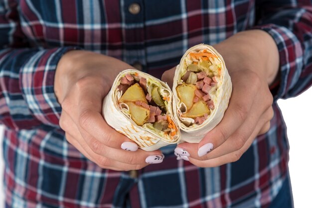 La mano della donna tiene il kebab di shawarma su un fondo bianco. Isolato