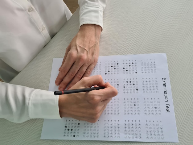 La mano della donna tiene la matita e segna le risposte per testare in esame