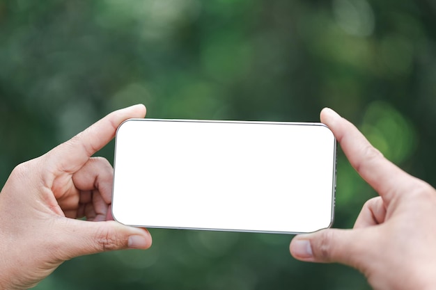 La mano della donna tiene lo smartphone moderno con schermo bianco su sfondo floreale Concetto di viaggio Idee per l'ufficio aziendale Scelta del viaggio Copia spazio Negozio online tecnologia cyberspazio digitale rete web