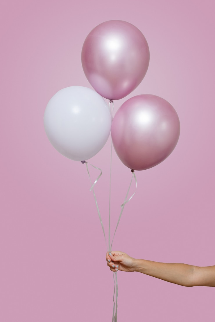 Foto la mano della donna tiene tre palloncini rosa e bianchi isolati su sfondo rosa con spazio per il testo