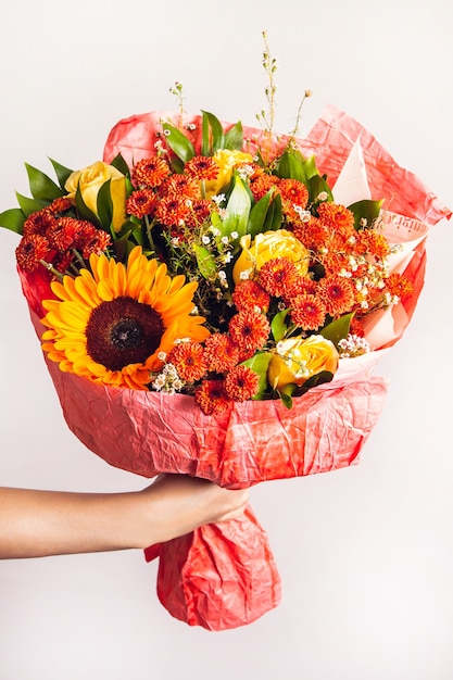 La mano della donna tiene un bouquet autunnale con un girasole