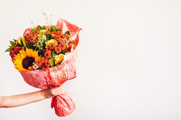 La mano della donna tiene un bouquet autunnale con un girasole