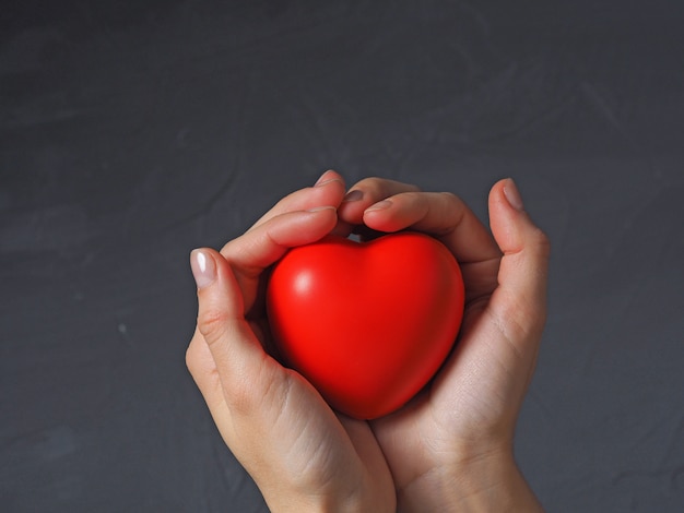 La mano della donna tiene un cuore rosso