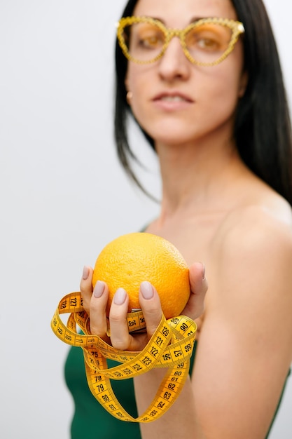 La mano della donna tiene un nastro lungo un centimetro e un frutto di limone Il concetto di uno stile di vita sano concetto di cibo biologico naturale