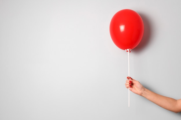 la mano della donna tiene un pallone rosso dell'Ir a disposizione sulla fine grigia del fondo su