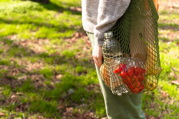 La mano della donna tiene una borsa verde in cotone ecologico con alimenti biologici.