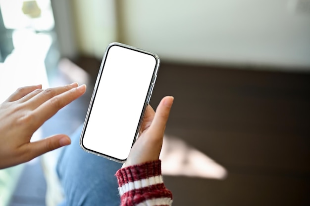 La mano della femmina che tiene un'immagine del primo piano del mockup dello schermo bianco del telefono cellulare