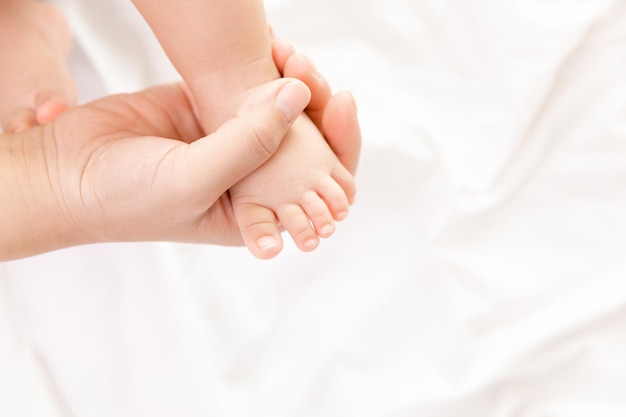 La mano della madre che tiene il neonato a piedi nudi