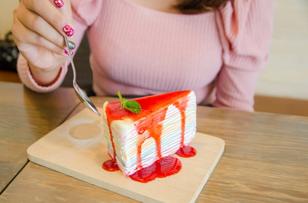 La mano della ragazza asiatica sta mangiando il dolce di crêpe