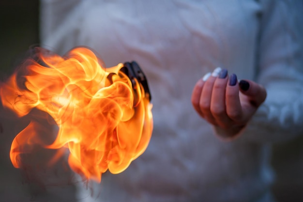 La mano della ragazza contro il fuoco. Mano bruciante. Simbolo luminoso Flamy. Fuoco in mano.