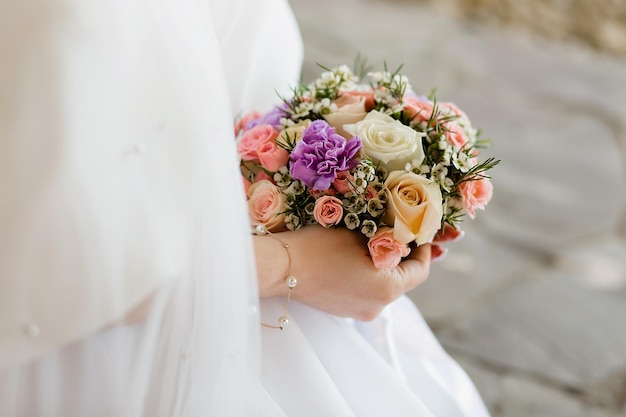 La mano della sposa che tocca il suo bouquet da sposa delicato