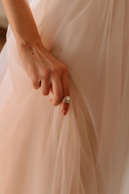 La mano delle ragazze sostiene l'orlo di un vestito elegante