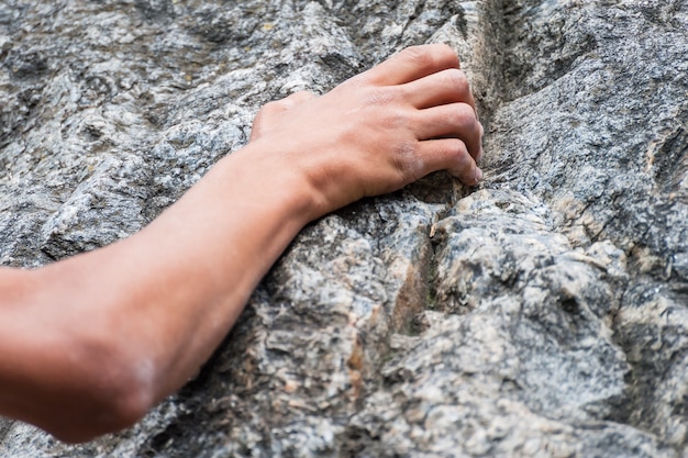 La mano dello scalatore che tiene saldamente una roccia, sport estremo