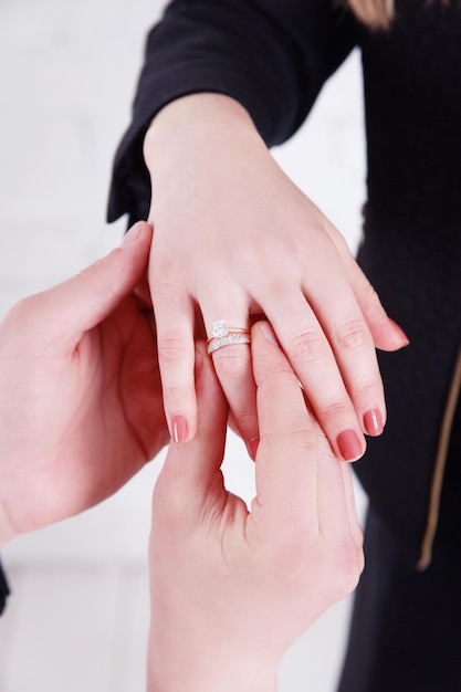La mano dello sposo che mette una fede nuziale sul dito della sposaMatrimonio