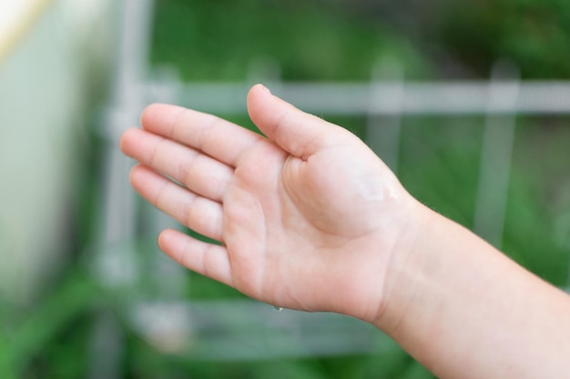 La mano di un bambino cattura una goccia d'acqua