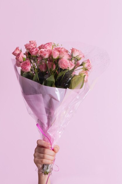 La mano di un bambino tiene un bouquet di rose rosa