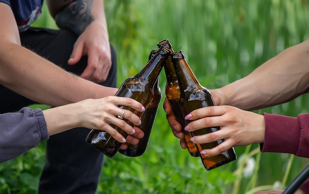 La mano di un uomo che tiene una bottiglia di birra in natura. riposa in riva al fiume. Natura. Messa a fuoco selettiva