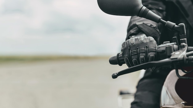 La mano di un uomo in guanti protettivi da moto tiene una moto nera da vicino