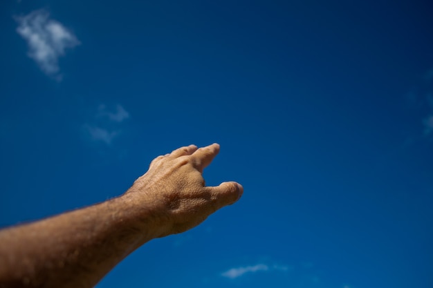 La mano di un uomo indica il cielo blu. simbolo di fede, obiettivo.